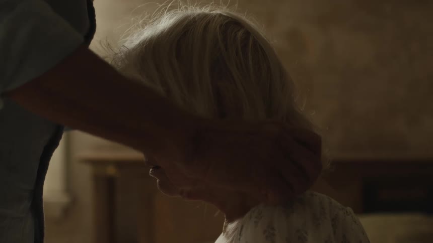 An old man dressing an old woman