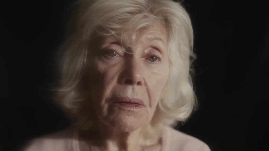 A lady with blue eyes and a sad look in a dark room