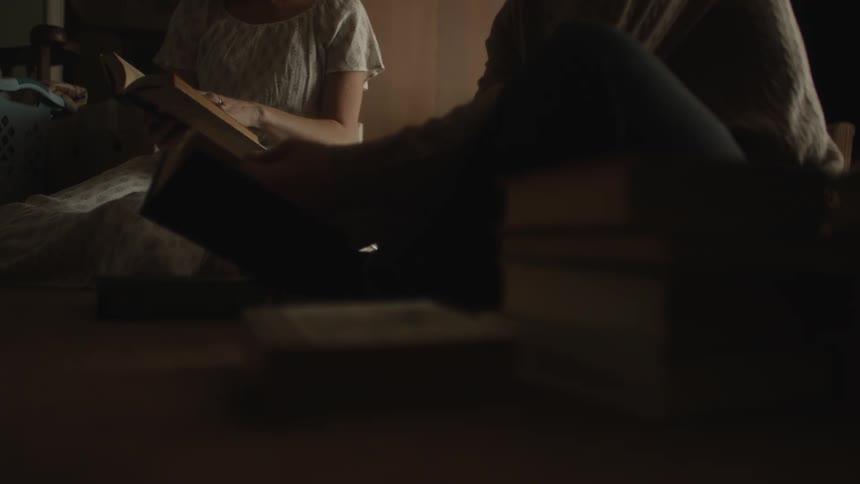 Two people are sitting on the floor and one of them is leafing through a book