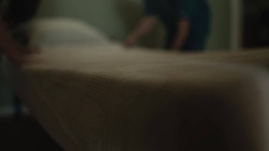 A male and female nurse laying a bed