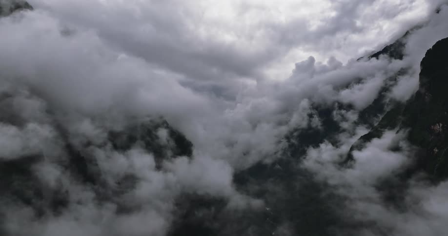 Heavy cumulus clouds cover dark mountain range