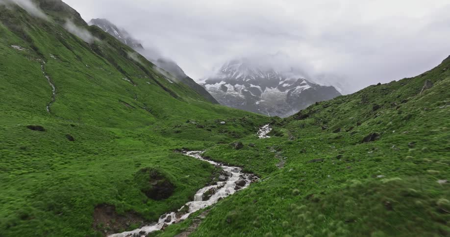 A mountainous grass land with a flowing stream