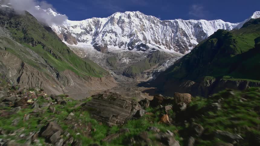 A landscape of a dry valley and several mountains and one of them is covered in snow