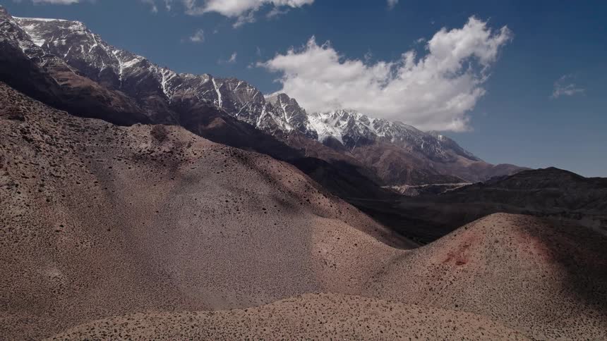 Rocky and desert mountains with a snowcovered mountain range on the horizon