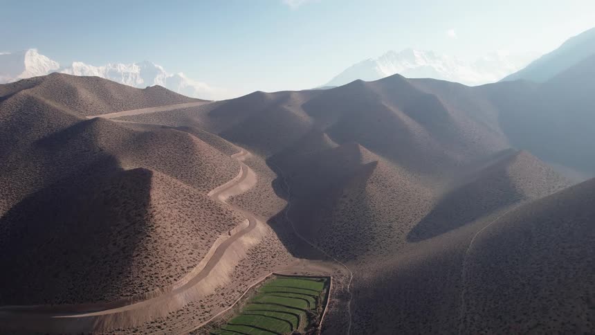 Aerial panorama of desert sand dunes with snowcovered mountain ranges in the background