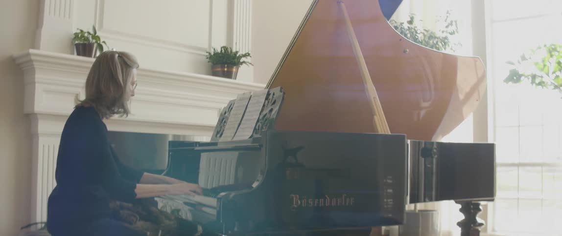 A woman is playing on a large grand piano