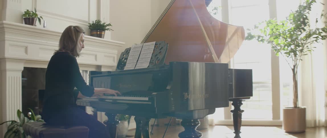 A woman wearing black plays a piano