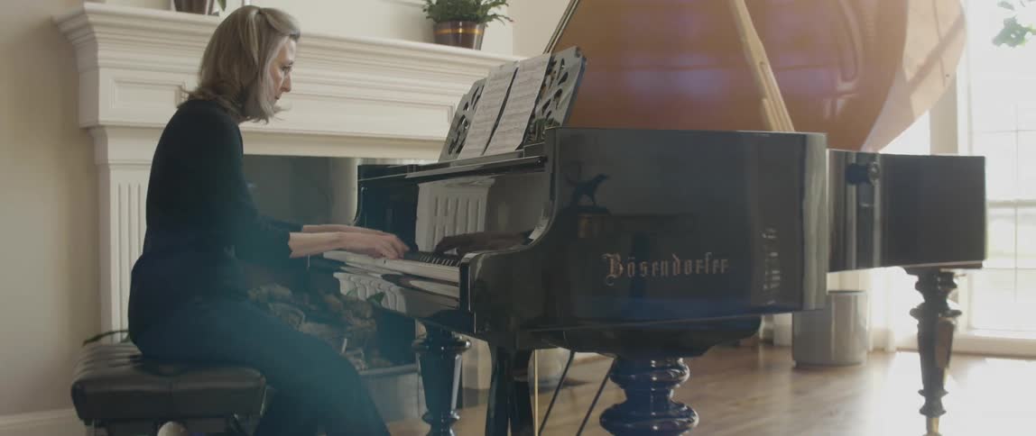Woman plays piano and reads off of sheet music
