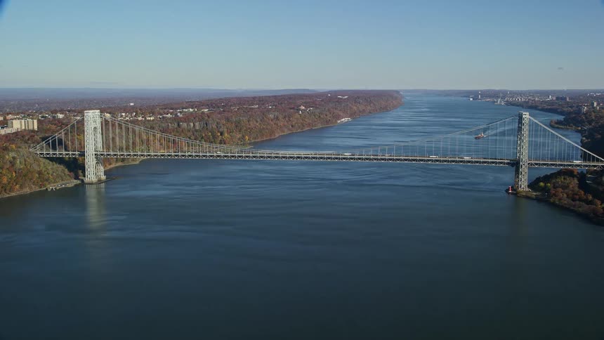 Traffic crosses suspension bridge over river separating sections of the city