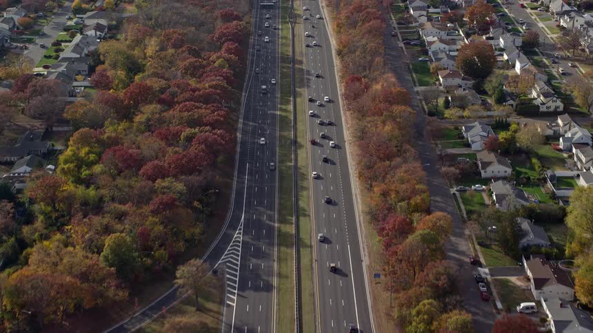 A large highway with several cars passing by and around it is a city with several small houses