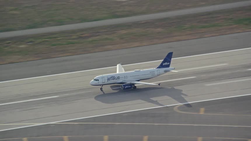 A jet airplane coasts on the tarmac as it takes off over the water
