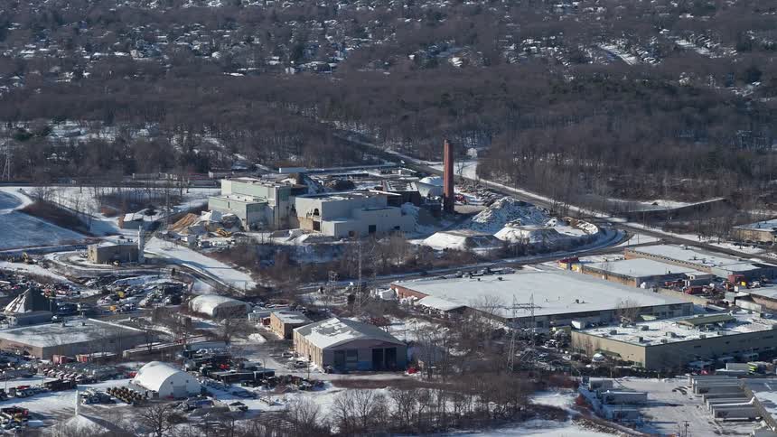 Aerial panorama of a factory amidst an urban city covered in winter snow