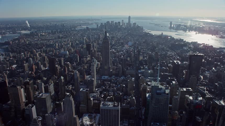A metropolitan city with huge buildings and on the horizon there is a sea