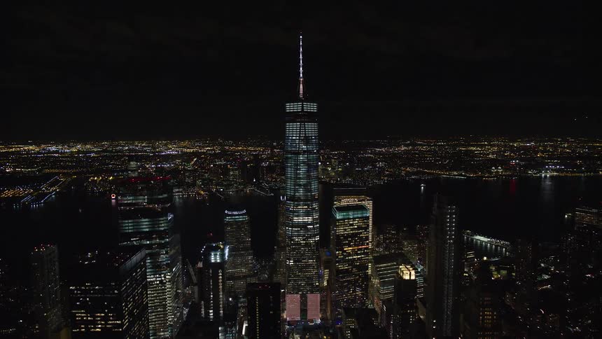 Aerial of one world trade center towering over nearby new york city skyscrapers at night