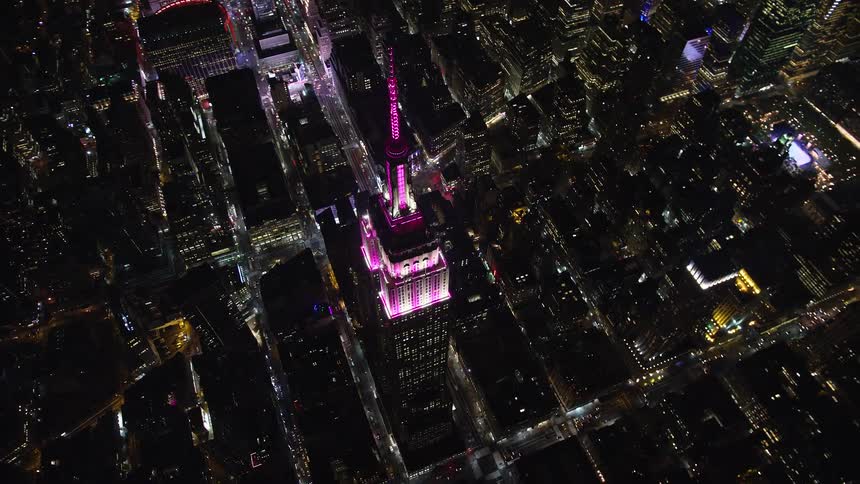 Aerial of spire building in a metropolitan area at night
