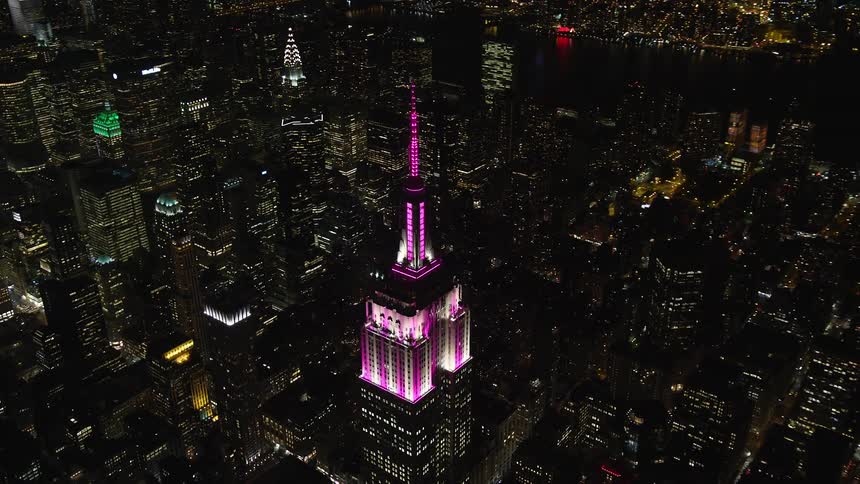Aerial of brightly lit empire state building towering over new york city scape at night