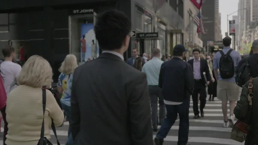 A large amount of people cross the street in a city
