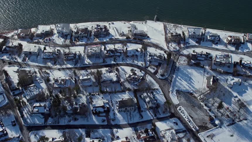 During winter a sub urban area close to shore is covered in snow