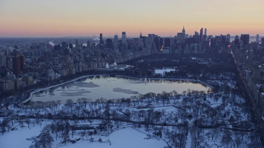 Aerial panorama of a metropolis with a central park covered in snow and a lake
