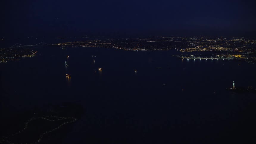 Aerial panorama of the sea surrounded by metropolises at night