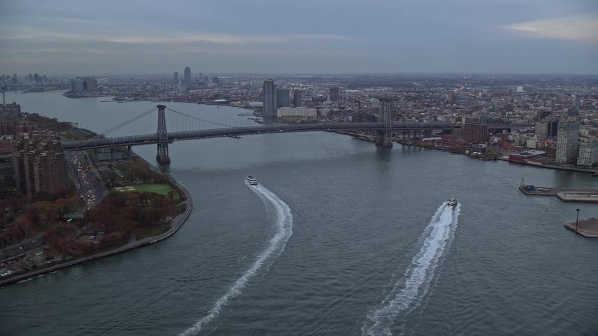 Two boats travel down the river by the city
