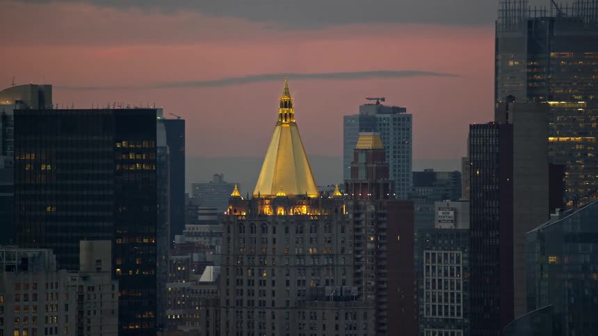 An aerial view of a golden tower in the midst of various skyscrapers