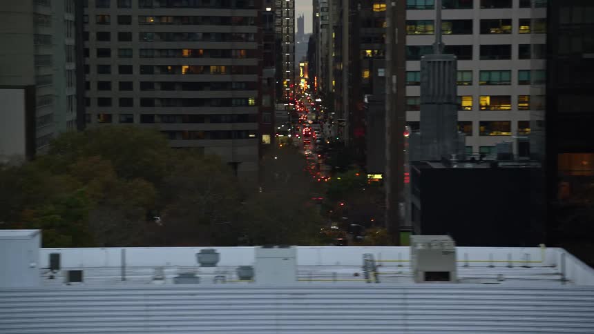 Buildings in a city are shown up close with roads of traffic between them