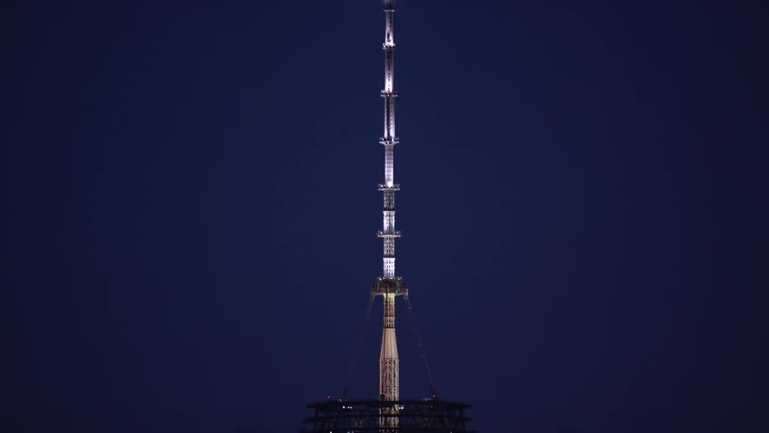 Tall antena atop a skyscraper at night