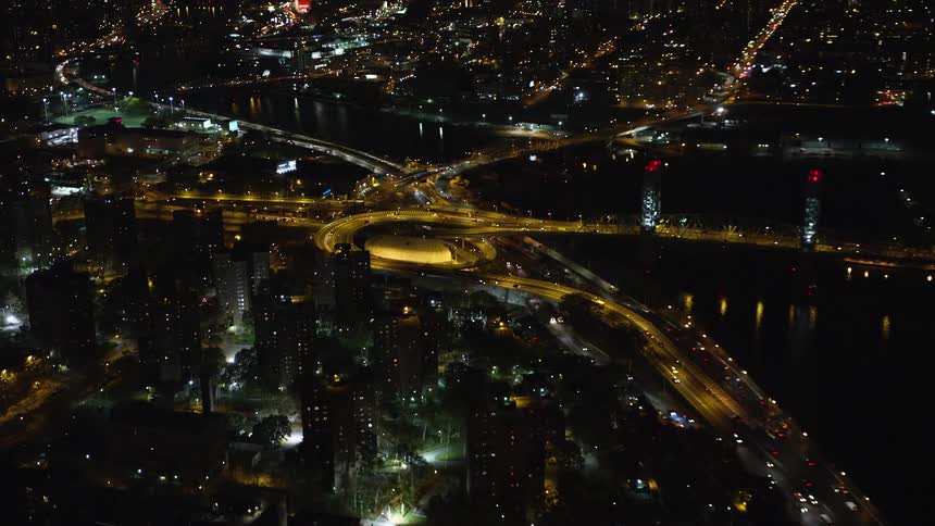 Aerial and panoramic view of a metropolis at night with waterfront skyscrapers and highways with traffic
