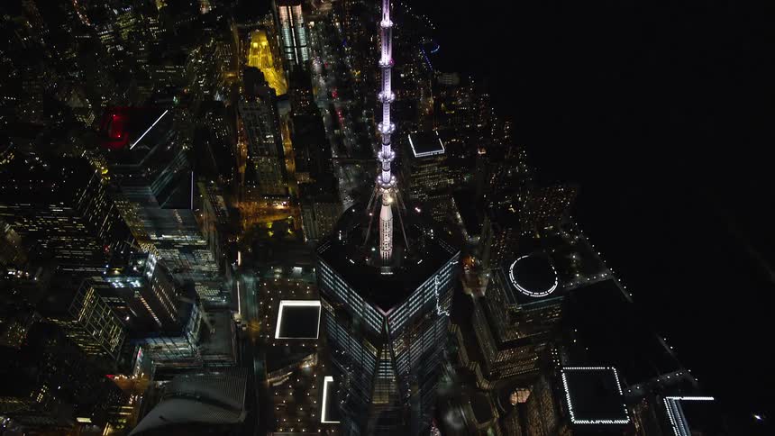 Aerial panorama of a metropolitan city by the seaside with a skyscraper illuminated at night