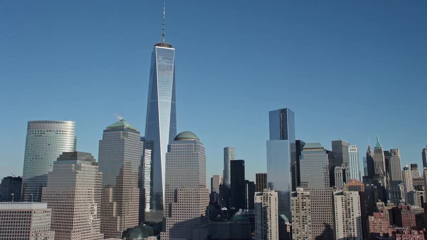 The sun shines upon towers and skyscrapers of a metropolitan city under a clear blue sky