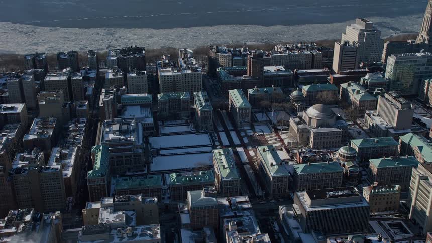 On a sunny day the view of a city filled with residential building mostly covered in snow as the season is winter