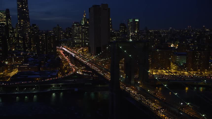 Aerial panorama of a metropolitan city with a bridge across the sea at night