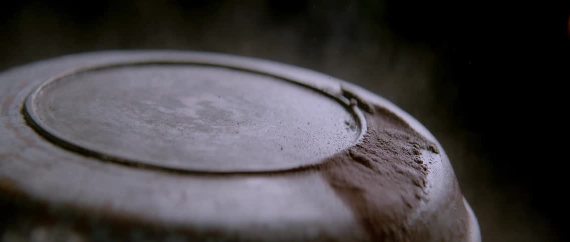 Spray expelling a brown and abstract layer over a round metallic object