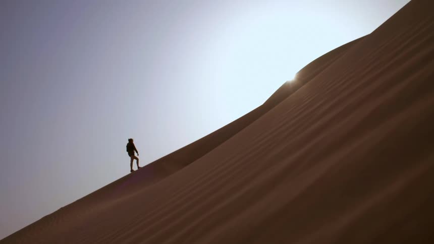 A person is hiking up the dune