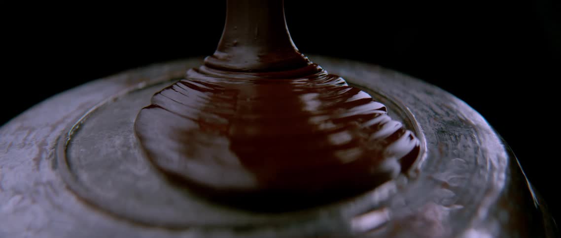 Dark food looking like chocolate falling into a plate