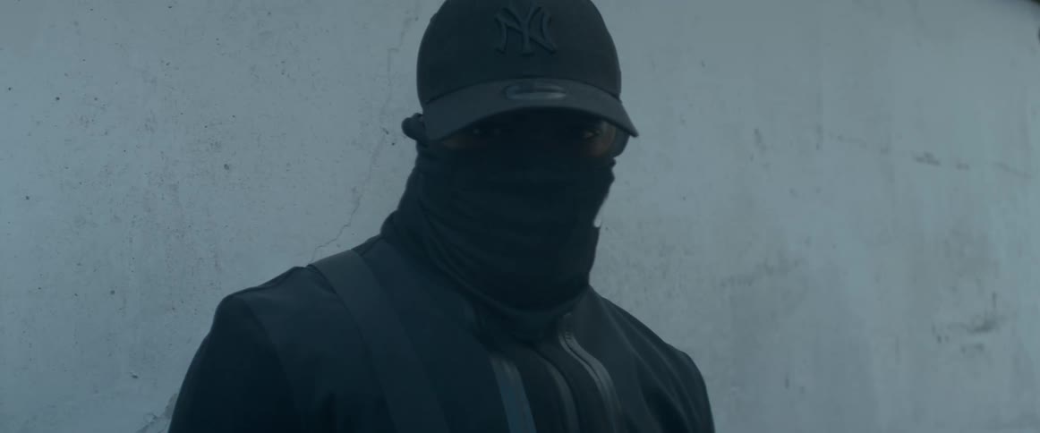 A person wears dark clothing and a face covering so they are intimidating