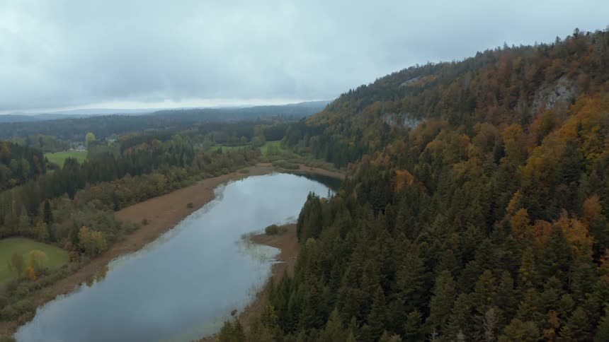 Aerial view of a pond in the countryside next to a mountain