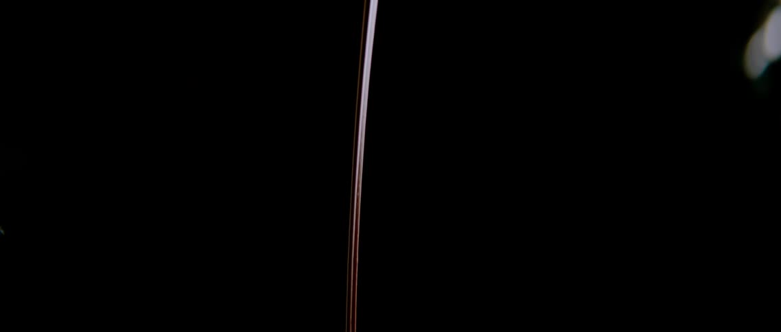 A person uses a tool to throw a string of liquid chocolate