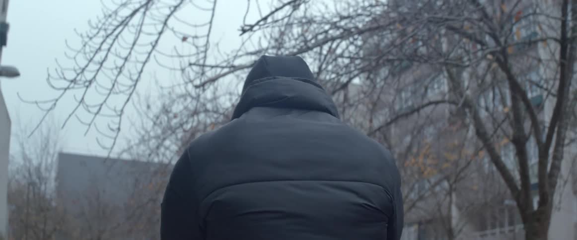 Man walking with his back turned in a city with apartment blocks