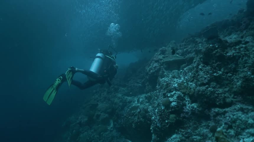 An underwater deep sea diver moving around the coral reef in the sea