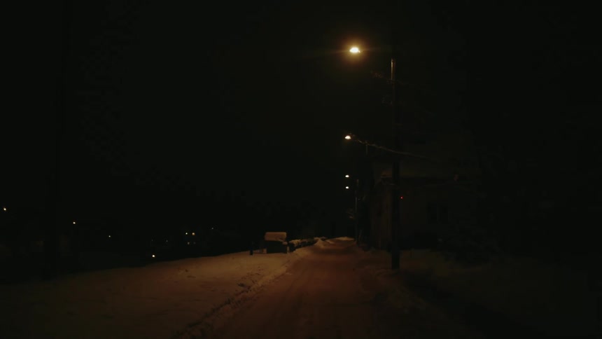 Snow covers partially blocked street at night