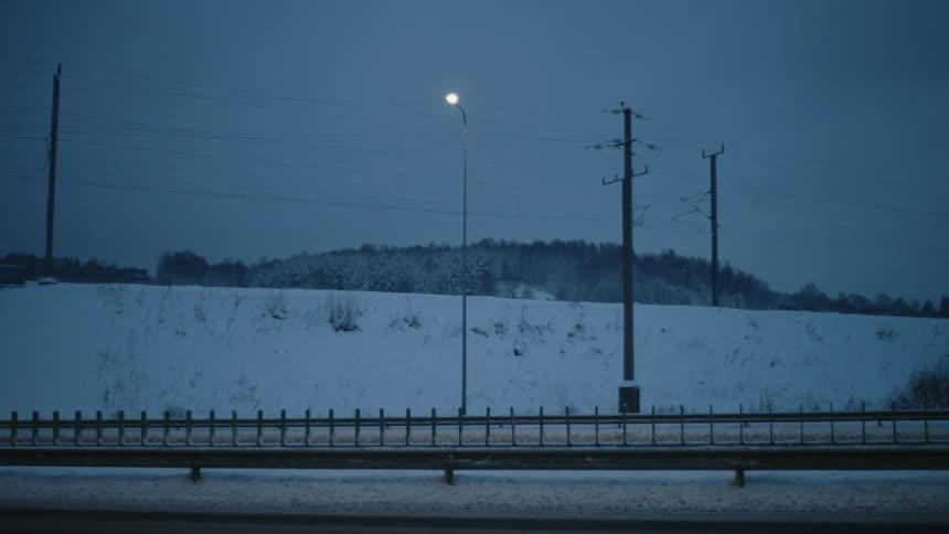 Moving cars on the road near power lines at dawn
