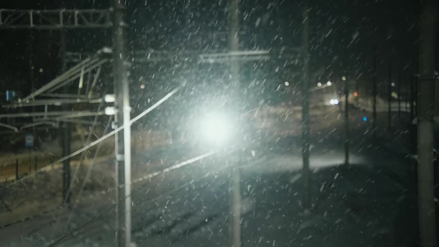 Two vehicles moving on a street with power lines on each side through a blizzard at night