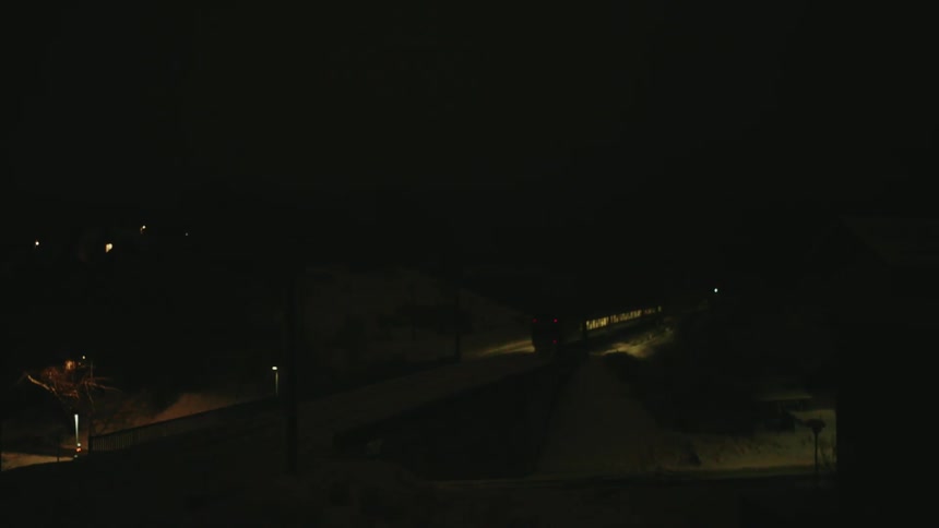 A train moves along tracks at night its lights cutting through the darkness