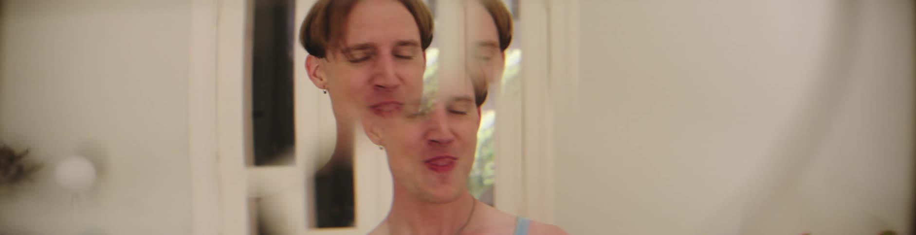 A man smiling while stretching his body in front of a mirror indoor at midday