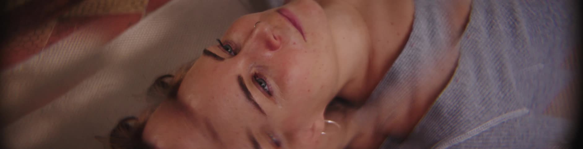 Woman lying on her back smiles while staring upward