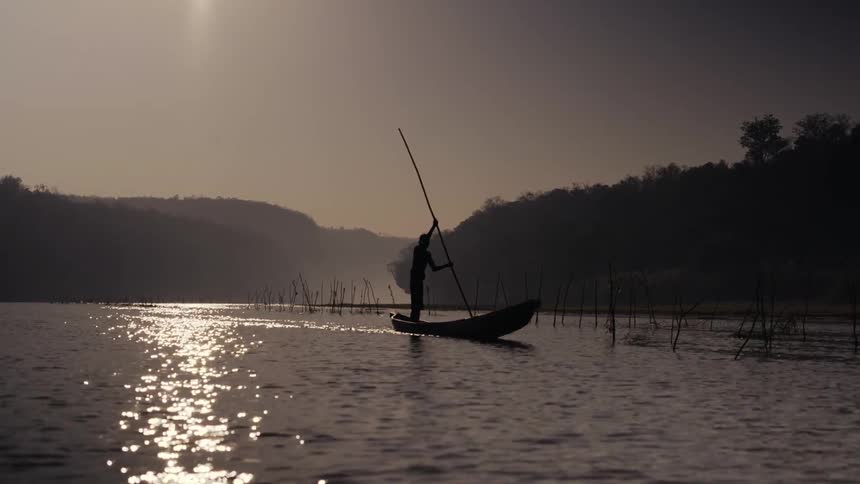 A man is rowing a small boat in the river