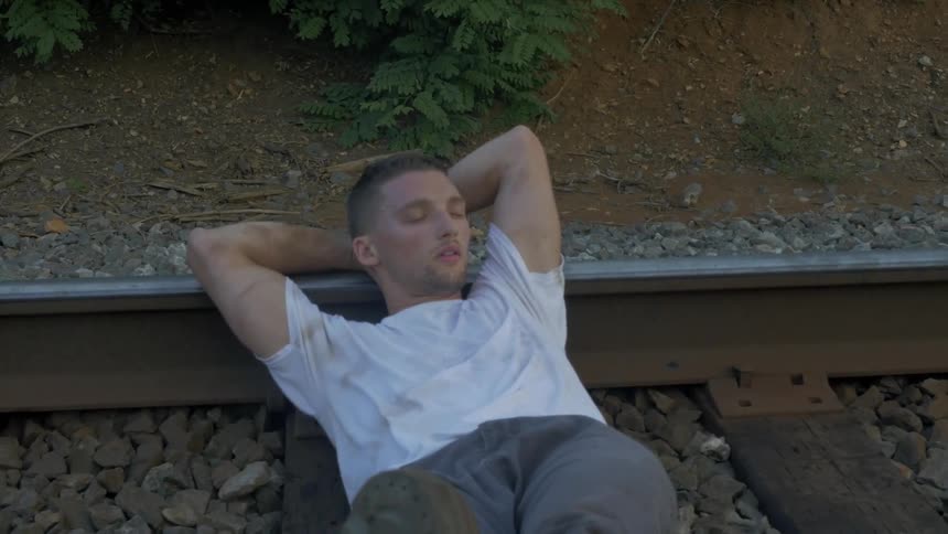 Man lying down on some railroad tracks