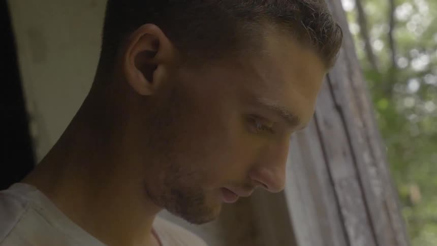 A man is looking down by a window